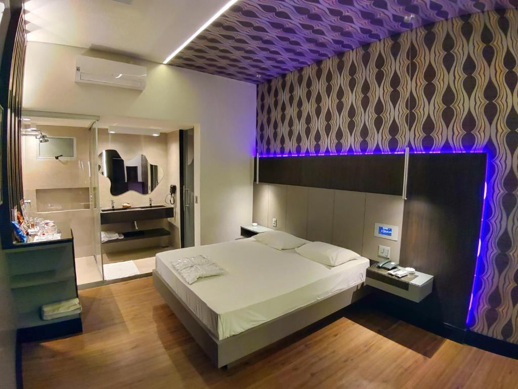 um quarto com uma cama grande e um tecto roxo em Motel Dallas em Belo Horizonte