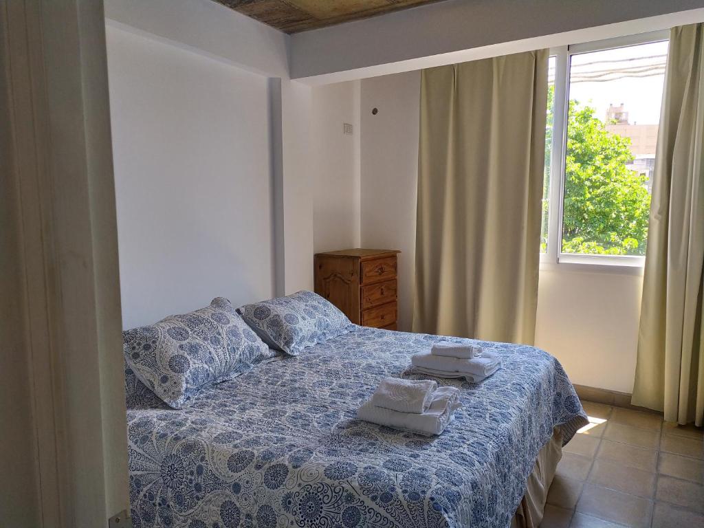 a bedroom with a bed with a blue comforter and a window at CASA MARGARITA 2P cuadruple in San Salvador de Jujuy