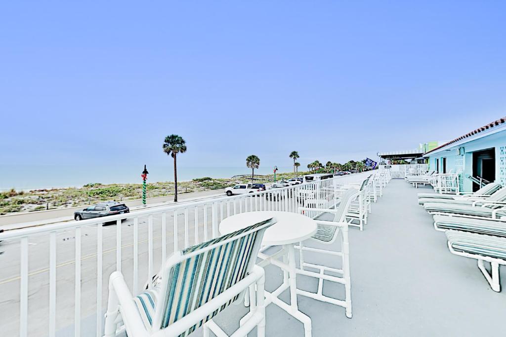 Pass-A-Grille Beach Retreat Unit 8 في سانت بيتي بيتش: صف من الكراسي البيضاء والطاولات على الشرفة