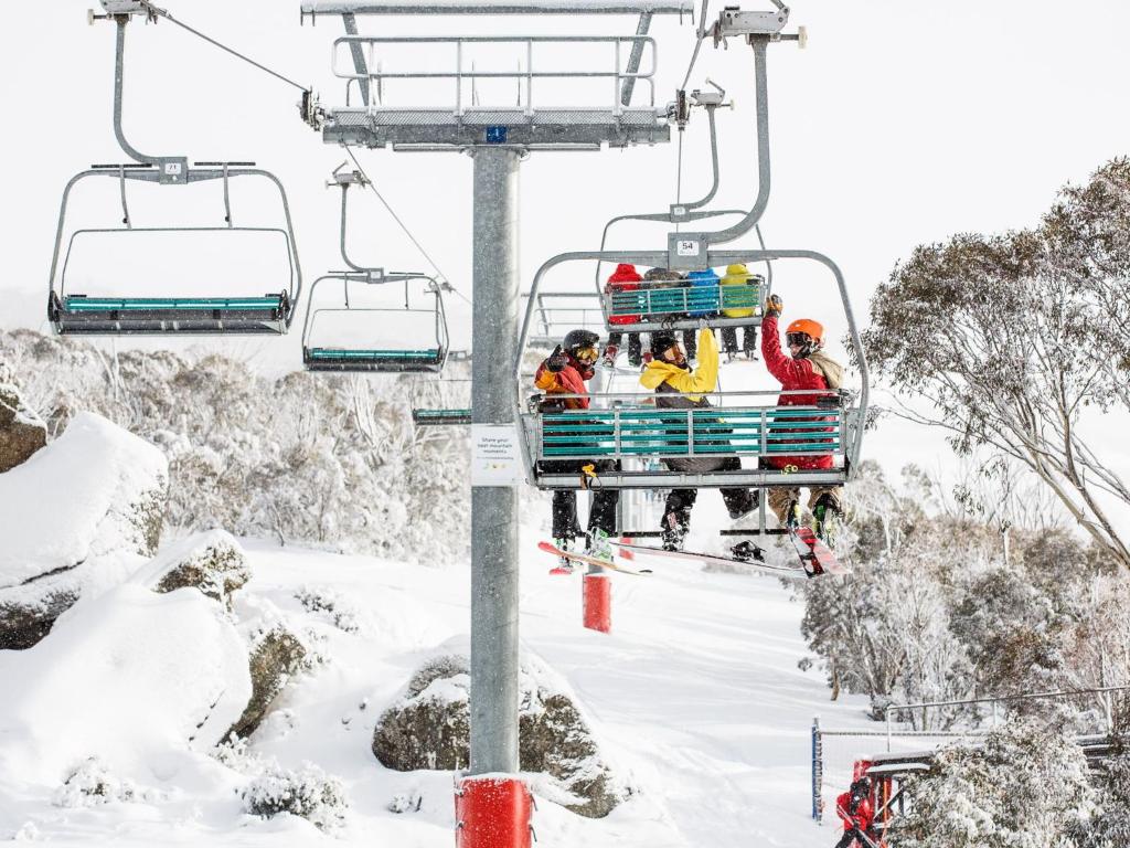 a group of people riding a ski lift in the snow at T Bar on Twynam - Modern 2BR Apartment l WiFi l Netflix l BBQ l Smart TV l Air-Con in Jindabyne