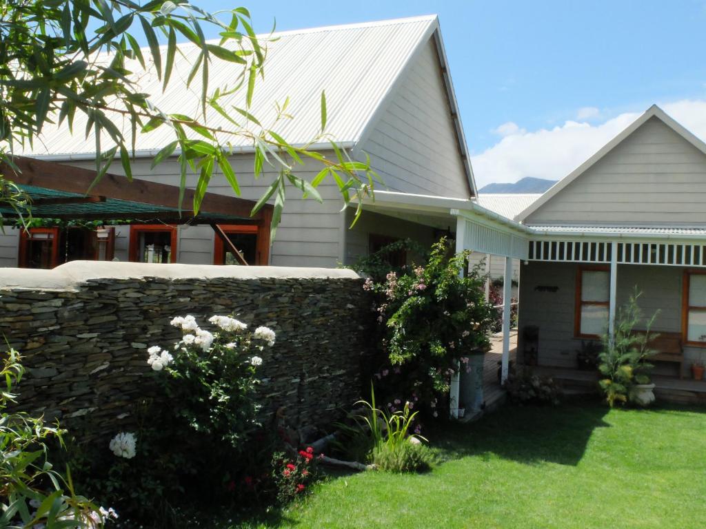a house with a stone wall and a fence at Doorways in Barrydale
