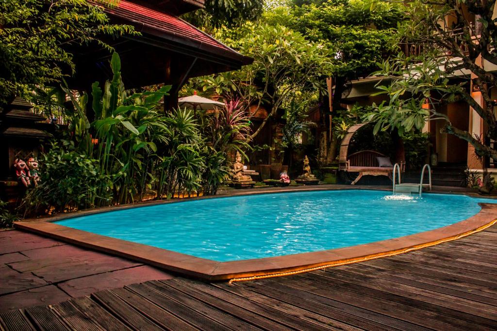 - une piscine dans une cour avec une terrasse en bois dans l'établissement Amata Lanna Chiang Mai, One Member of the Secret Retreats, à Chiang Mai