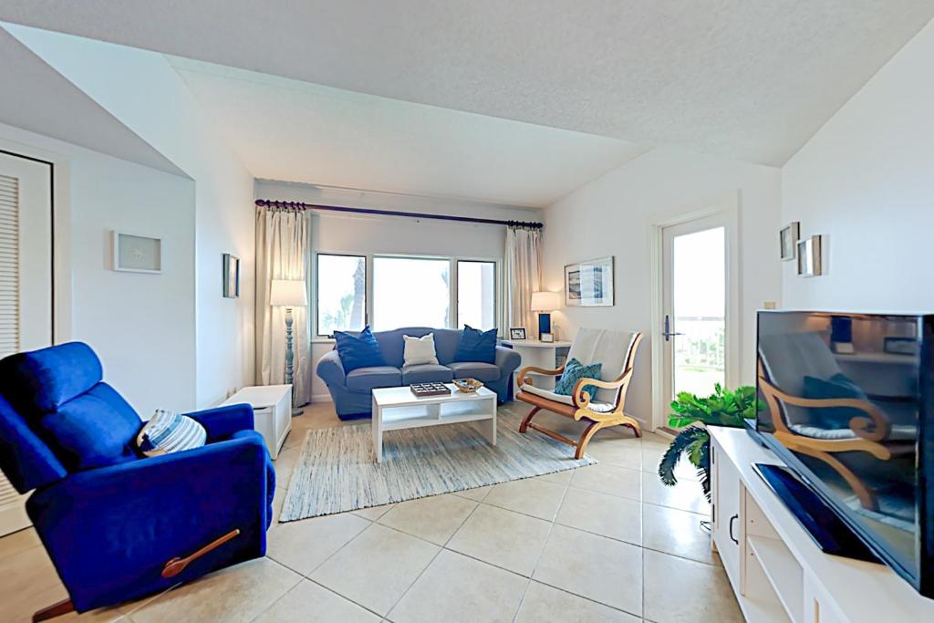 uma sala de estar com um sofá azul e uma televisão em Sandcastle Villas 215-216 em Fernandina Beach