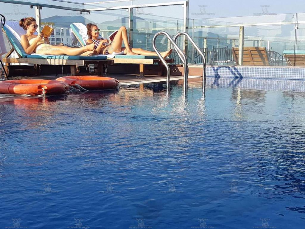 three women laying on chairs next to a swimming pool at Dana Marina Boutique Hotel in Danang