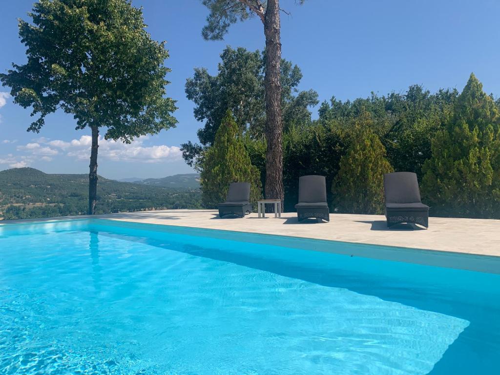 een zwembad met twee stoelen en een tafel en bomen bij Villa du defens in Saint-Martin-de-Castillon