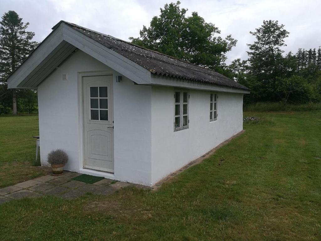 un pequeño cobertizo blanco con una puerta en un patio en Hærvejsly - Perfekt familiebase til oplevelse af Sydjylland en Give