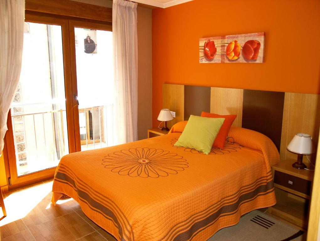 1 dormitorio con 1 cama con colcha de color naranja en Apartamentos Barrosa II, en Portonovo