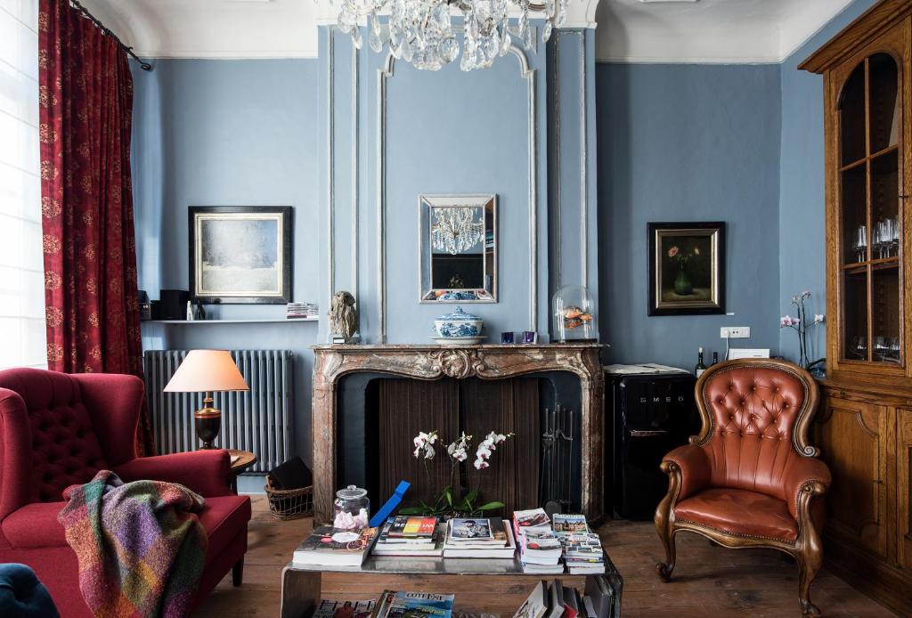 een woonkamer met blauwe muren en een kroonluchter bij Ganda Rooms & Suites in Gent