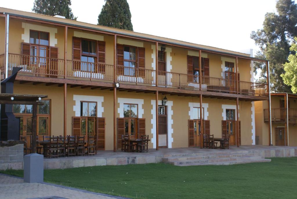 a yellow building with tables and chairs in front of it at Chargo Boutique Lodge in Colesberg