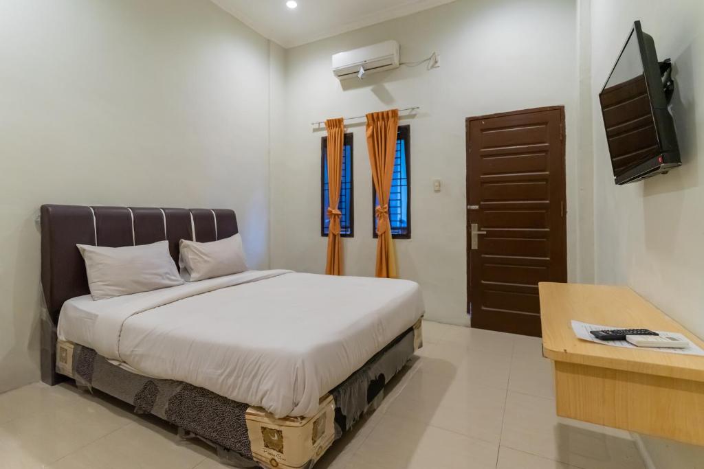 um quarto com uma cama e uma televisão em Vandolia Guest House Mitra RedDoorz em Medan