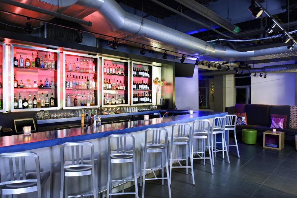 a bar with stools in a room with alcohol bottles at Aloft Cleveland Downtown in Cleveland