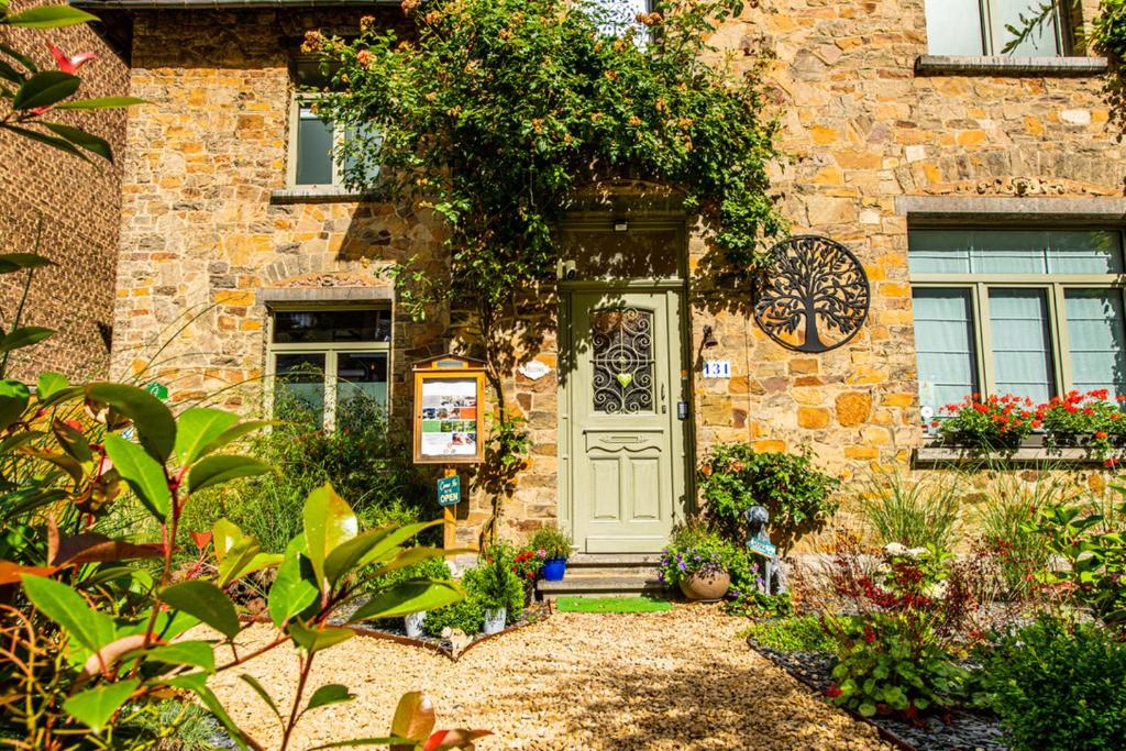 a stone house with a white door and plants at Le jardin des secrets in Namur