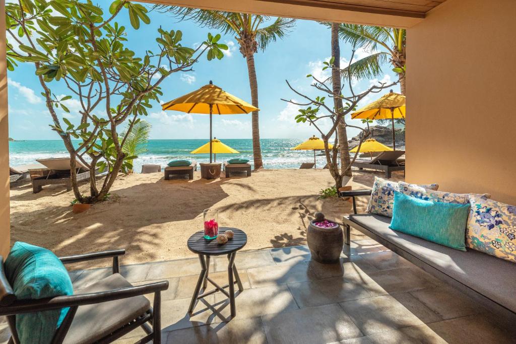 a living room with a couch and a view of the beach at Buri Rasa Village Phangan in Thong Nai Pan Noi