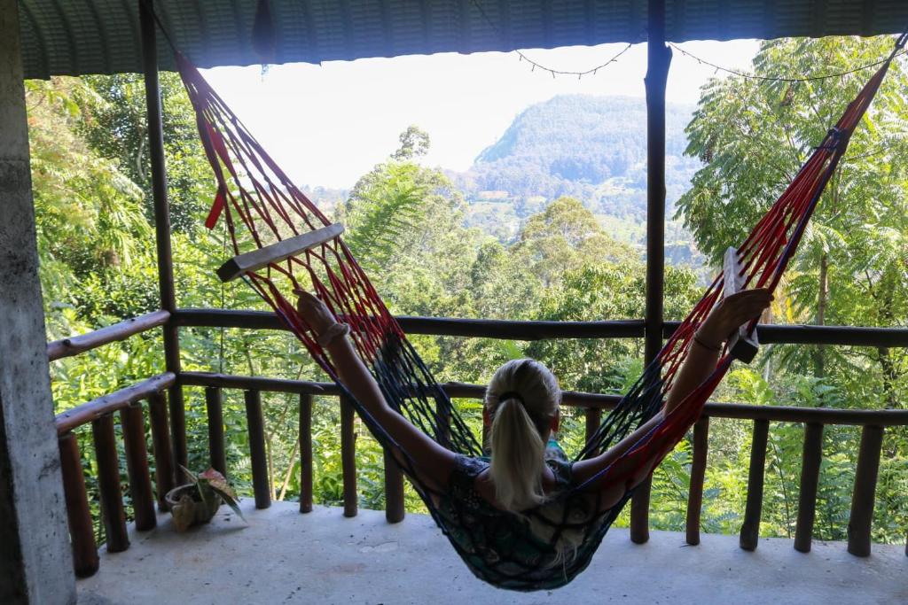 a woman is lying in a hammock on a porch at Nice View guest house & restaurant in Ella