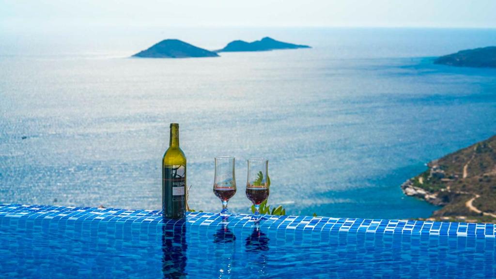 カルカンにあるEco Villa Palmiyeのスイミングプールの端に座るワイン2杯