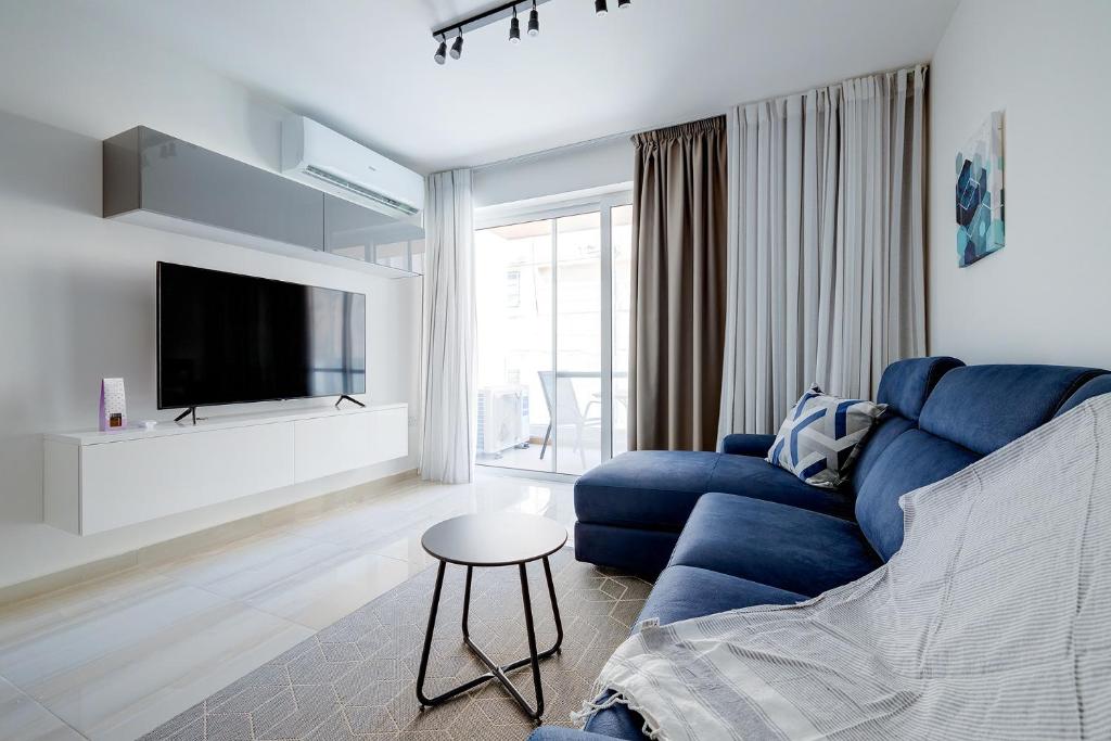 un salon avec un canapé bleu et une télévision dans l'établissement Chic 2BR Apartment, Ideal Location, à Taʼ Xbiex