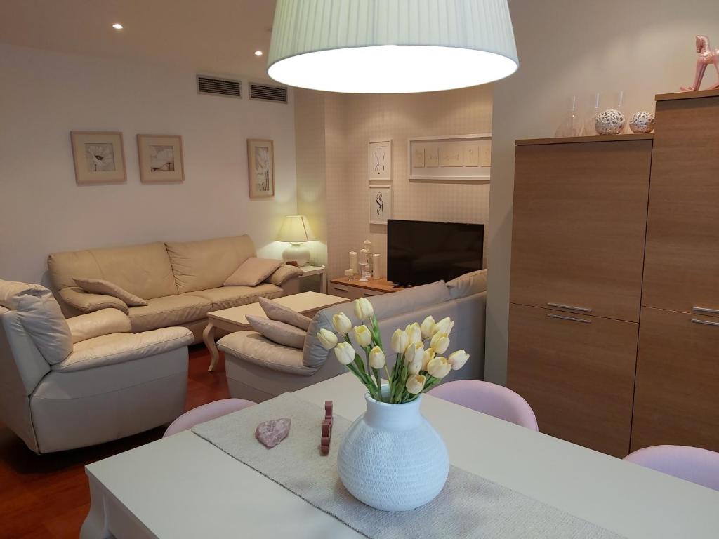 una sala de estar con un jarrón de flores sobre una mesa en Apartamentos Alcañiz, Deluxe, en Alcañiz