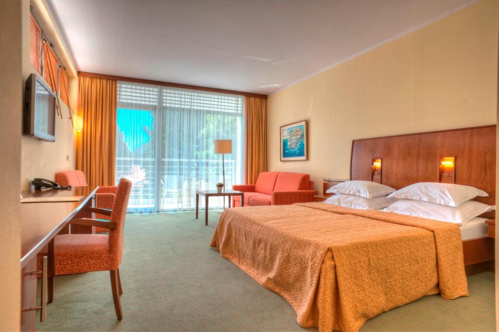 Habitación de hotel con cama, mesa y sillas en Hotel Rivijera, en Petrovac na Moru