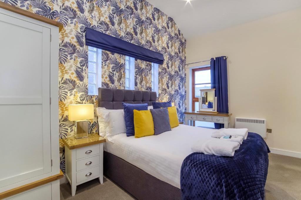 sypialnia z dużym łóżkiem z niebieskimi i żółtymi poduszkami w obiekcie City Apartments - Reubens Court w mieście York