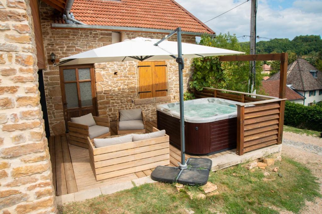 bañera de hidromasaje con sombrilla en un patio en Gîte le Troisième- gitesdesbalcons-com, en Panossas