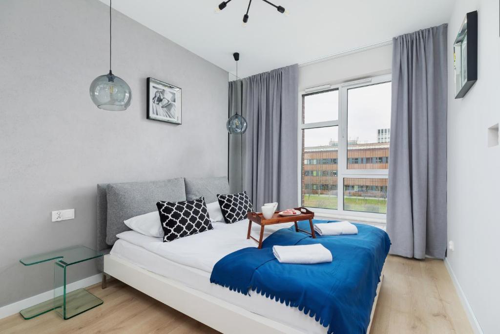 1 dormitorio con 1 cama con manta azul en Lotniczówka Apartments by Renters Prestige, en Cracovia