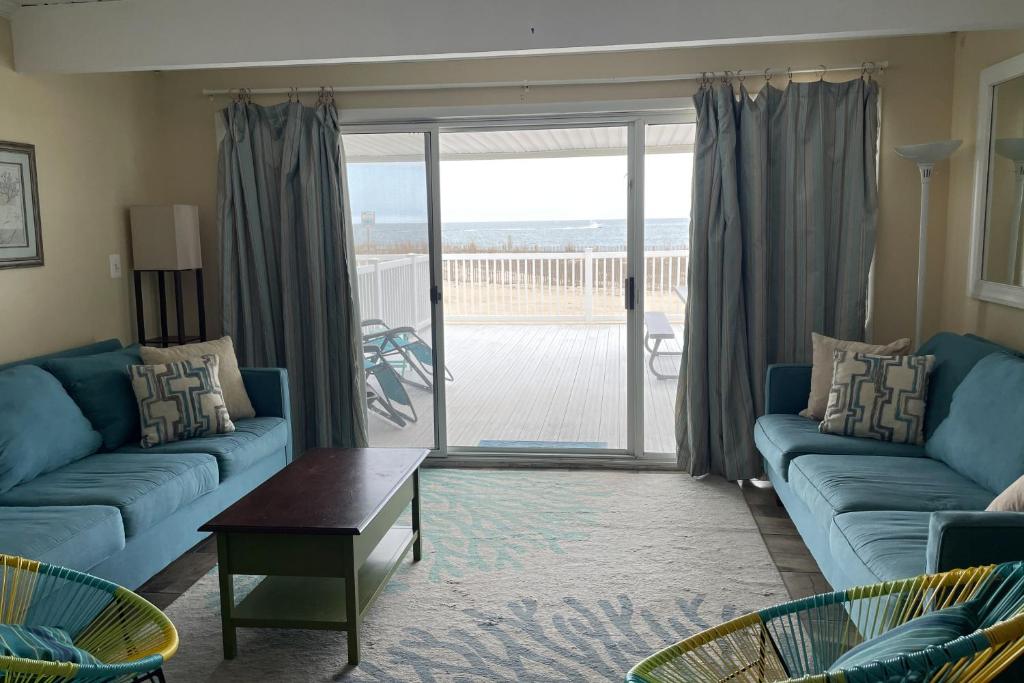 a living room with blue couches and a sliding glass door at Ocean Colony 3 in Ocean City