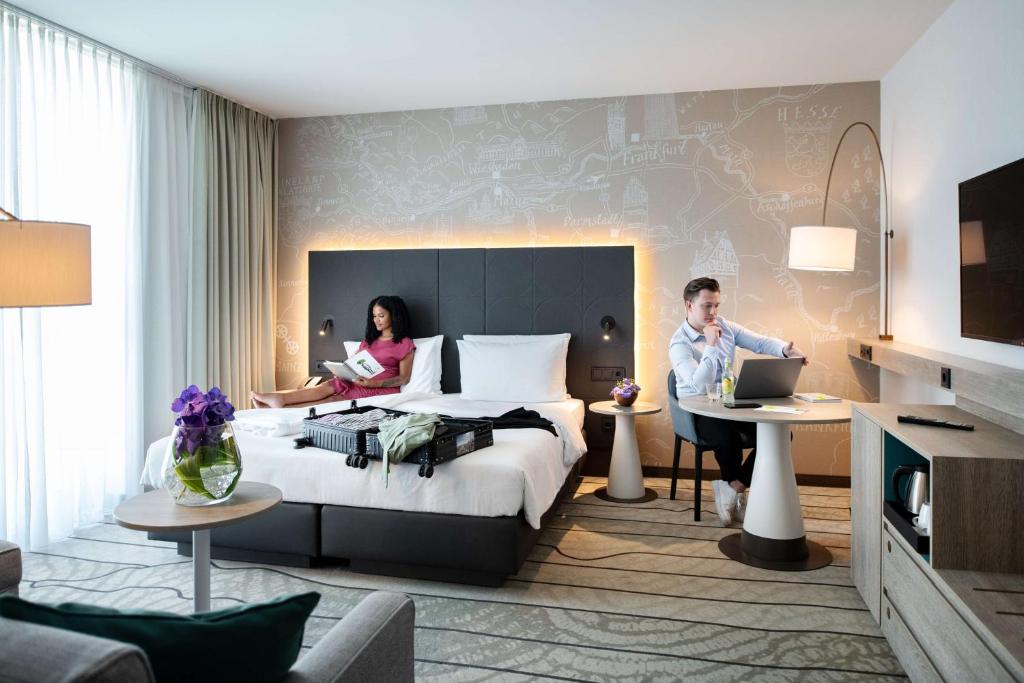 
a hotel room with two people sitting on couches at Hyatt Place Frankfurt Airport in Frankfurt
