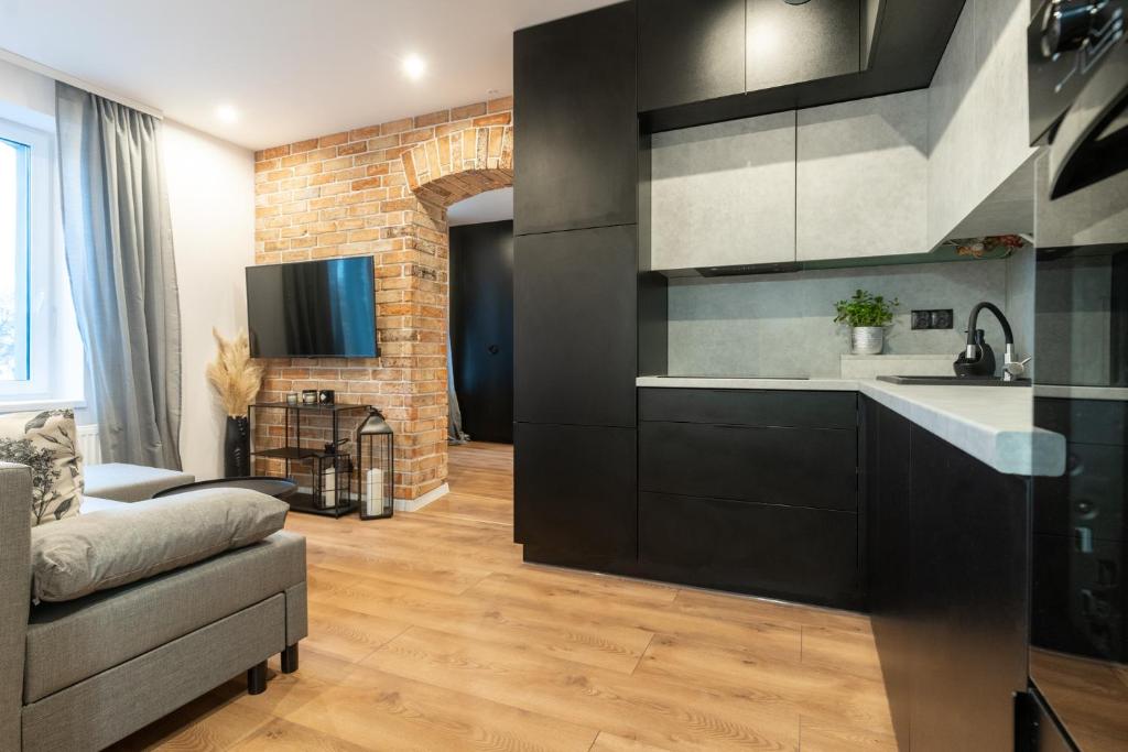 a kitchen with black cabinets and a brick wall at Apartament Królowa Luiza in Zabrze