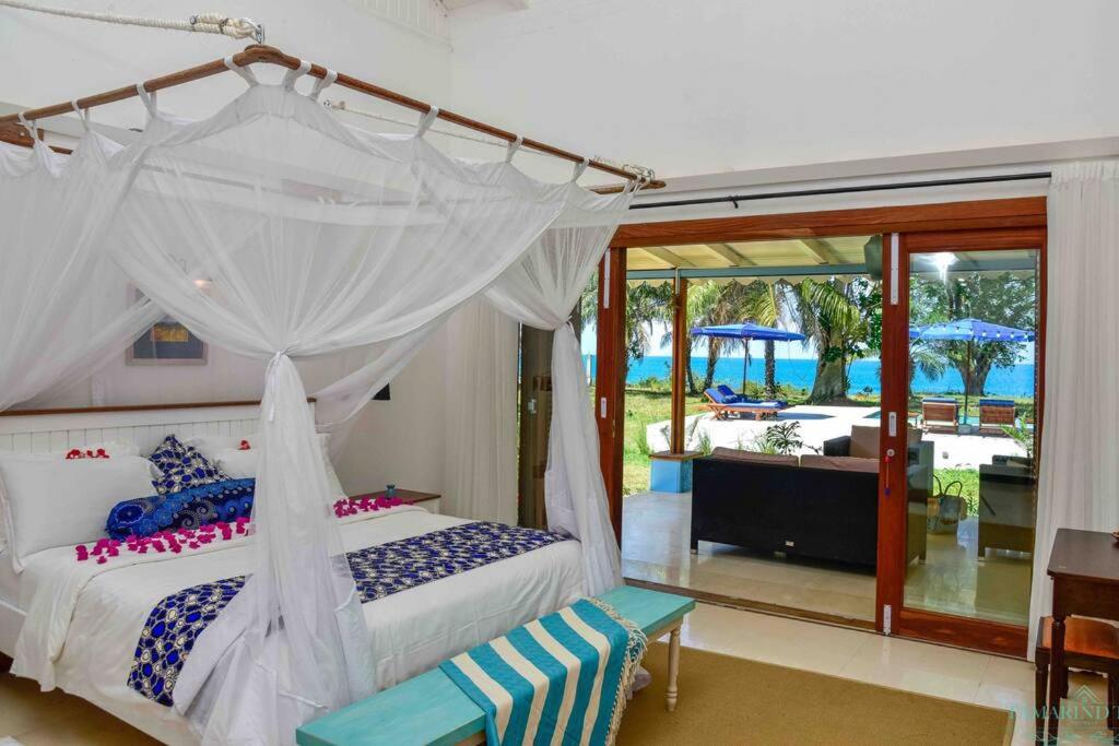 a bedroom with a canopy bed with a view of a pool at Tamarind Tree Zanzibar in Mazizini