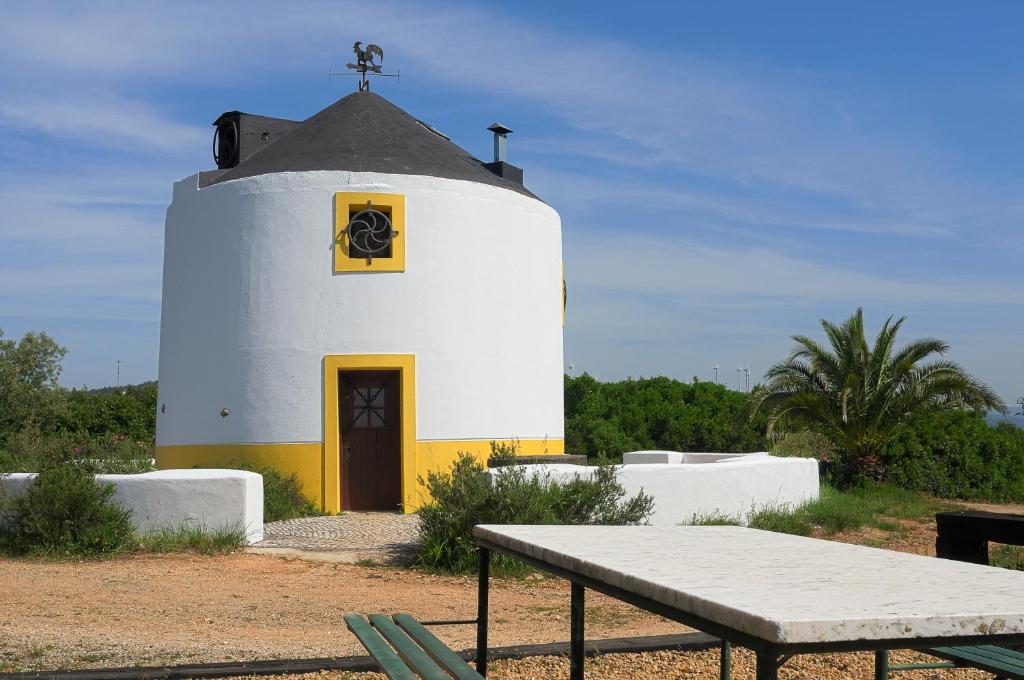 a white lighthouse with a bench in front of it at Moinho da Senta in Rio Maior