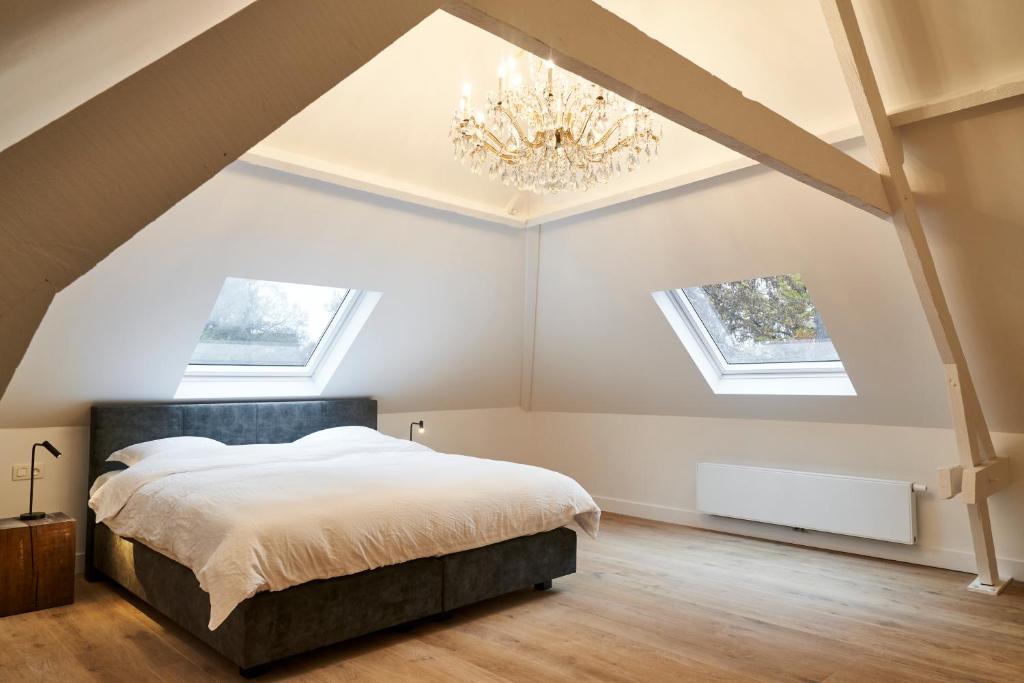 1 dormitorio con cama y lámpara de araña en Moleneinde 10, en Weelde