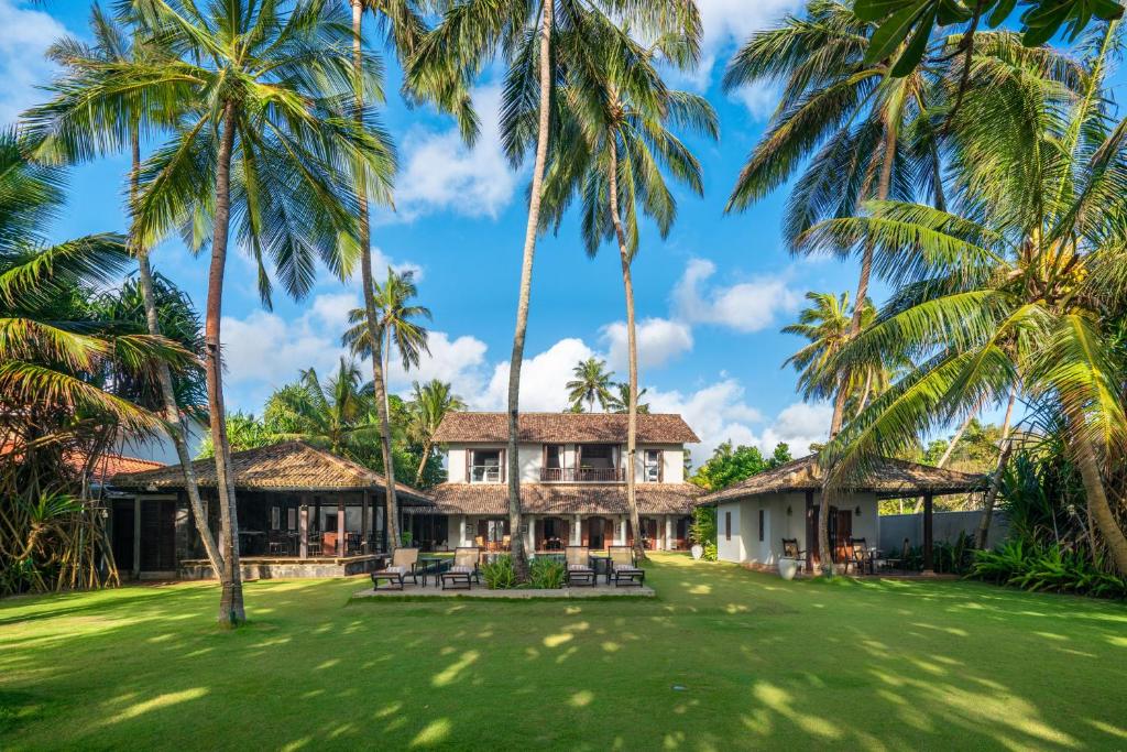 an exterior view of a house with palm trees at Sundara by Mosvold in Balapitiya