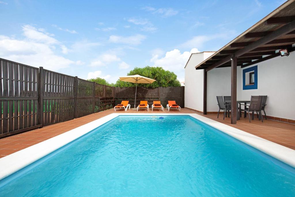 a pool with chairs and an umbrella on a deck at Villa Susana in La Oliva