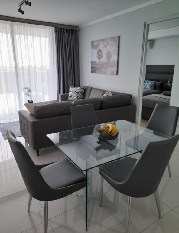 a living room with a glass table and a couch at Stylish Modern 2BR in Waterfall Ellipse - Sleeps 4 - Fast WiFi - Secure Parking in Midrand