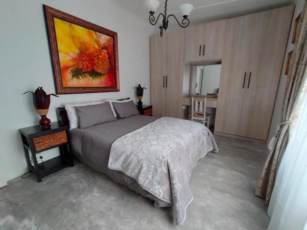 een slaapkamer met een bed en een schilderij aan de muur bij 7-on-Burger in Polokwane