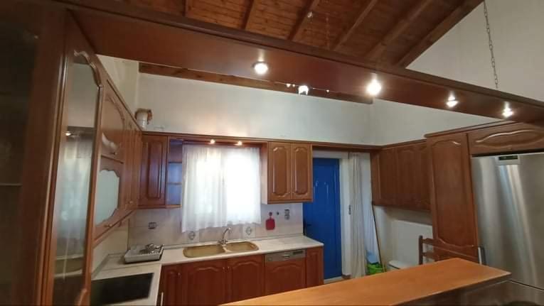 eine Küche mit Holzschränken, einem Waschbecken und einem Fenster in der Unterkunft Melana Apartment in Tiros