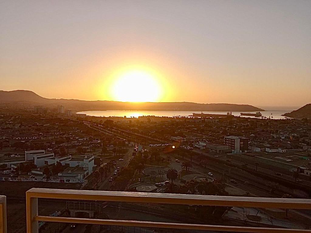 a view of a city with the sun setting over the water at Departamento Coquimbo La Serena in Coquimbo