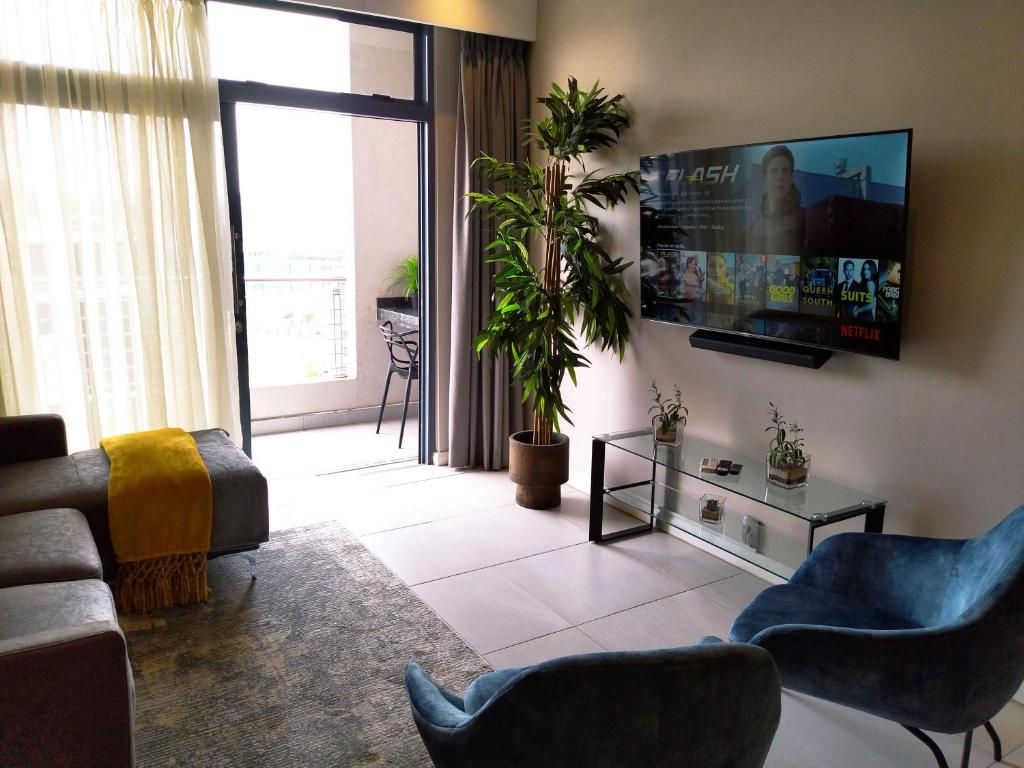 a living room with a flat screen tv on a wall at Trilogy Apartment - Sapphire Gold in Pretoria