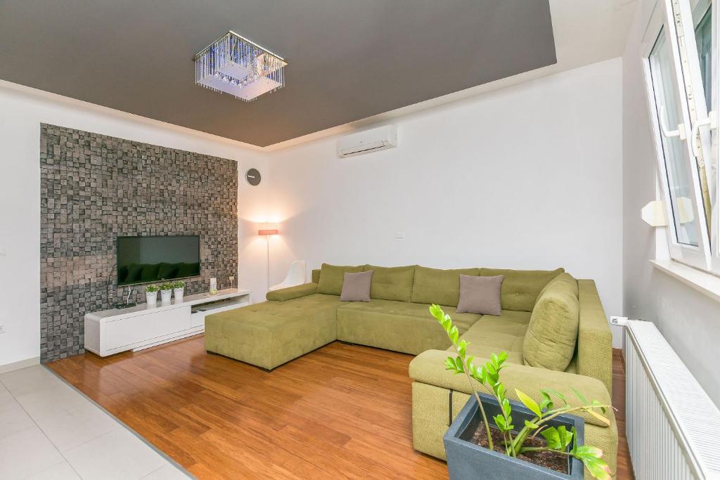 a living room with a green couch and a tv at Apartment Mario in Strožanac