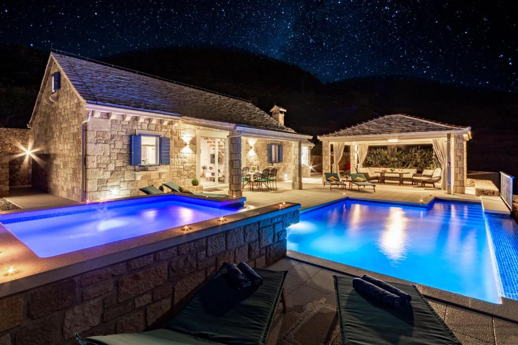 a swimming pool in front of a house at night at Villa Blue Sky in Bol