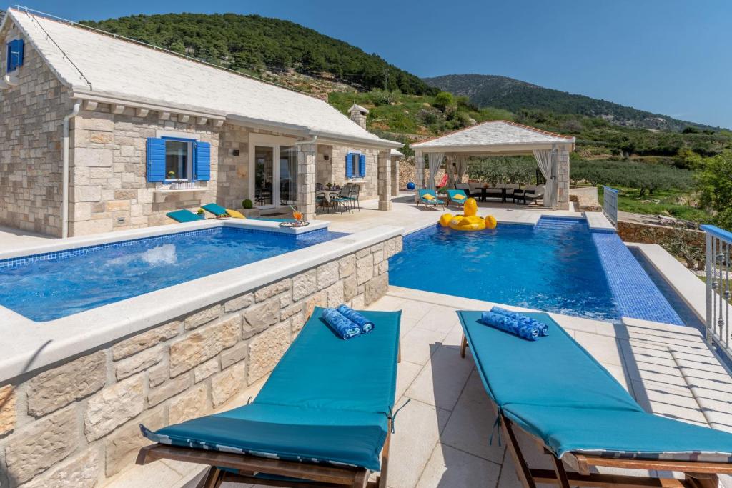a swimming pool with two blue chairs next to a house at Villa Blue Sky in Bol