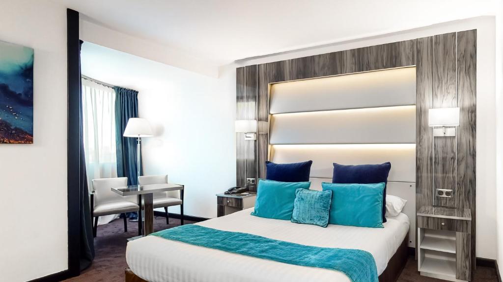 a bedroom with a large bed with blue pillows at Hotel Palladia in Toulouse