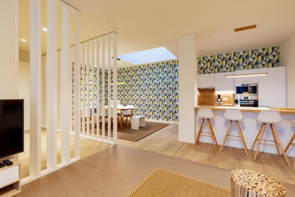 a kitchen and living room with a counter and a tv at GUILLEMINS STATION FLATS in Liège