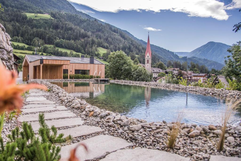 a small village with a church and a body of water at Chalet & Appartement Zingerlehof Trens in Campo di Trens