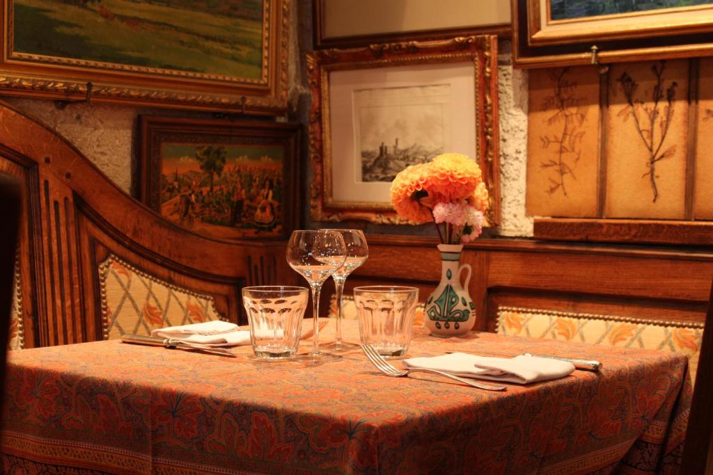 a doll sitting on a table with a vase of flowers at Hôtel Restaurant Le Schlossberg in Zellenberg