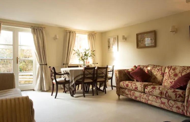 a living room with a table and a couch at Old Forge Close, Pretty 3 Bed Cottage in Bledington, The Cotswolds in Bledington