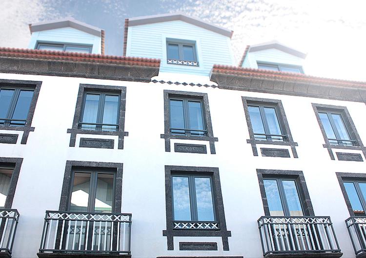 um edifício branco com janelas e varandas pretas em Faial Marina Apartments 1 em Horta