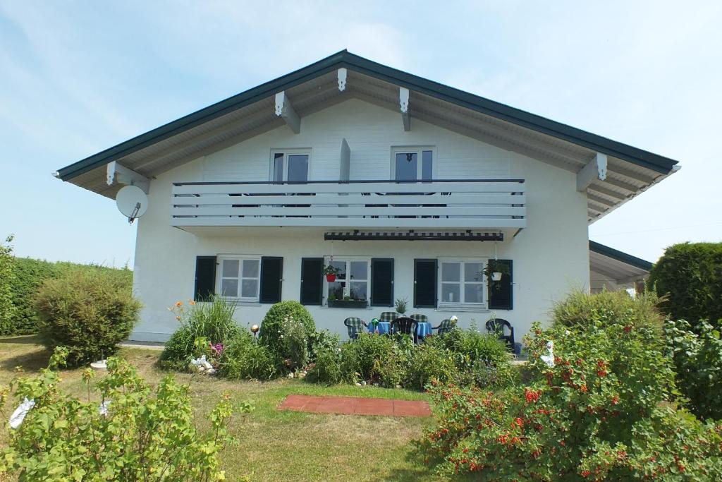 a white house with black windows and bushes at Haus Chiemseeblick in Grabenstätt