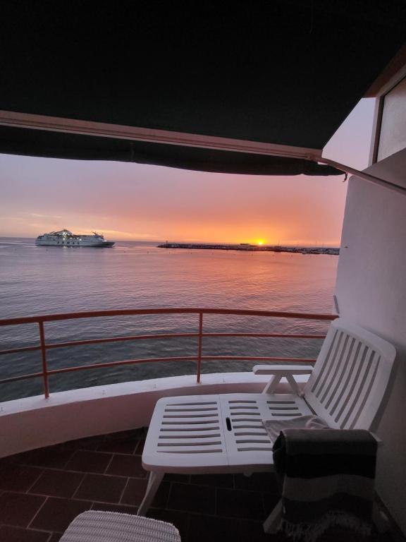 einen Balkon mit einem Stuhl und einem Sonnenuntergang auf einem Schiff in der Unterkunft Cristianmar, Los Cristianos in Los Cristianos