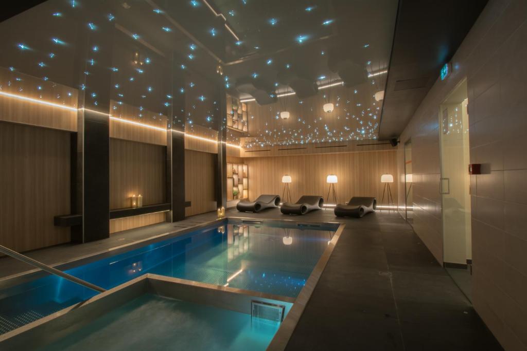 a swimming pool in a hotel room with lights on the ceiling at L' Hôtel & Spa Ribeauville- Haut-Koenigsbourg in Ribeauvillé
